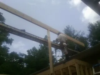 Carpenter setting a ridge beam over a new addition frame — Ice Dam Removal by Roofing Brothers in Parkton