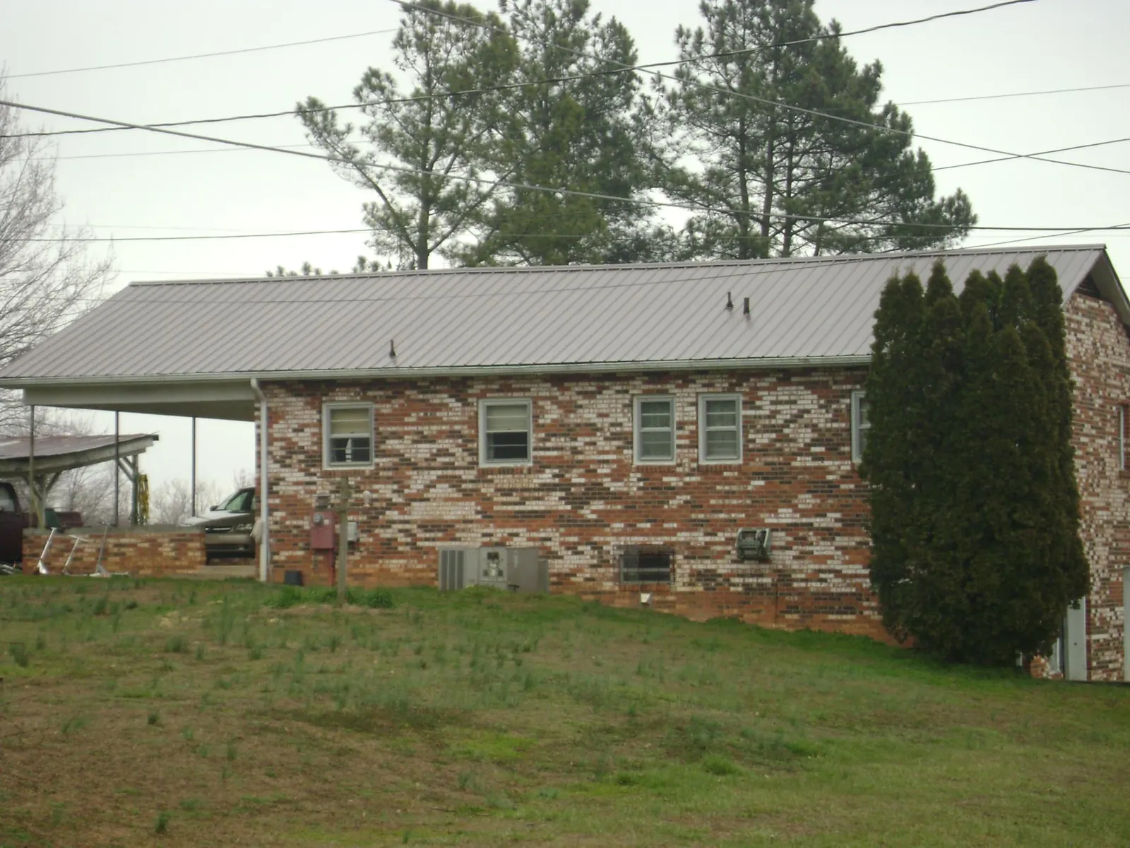 Gray metal roof on a brick split level home with a carport in Parkton