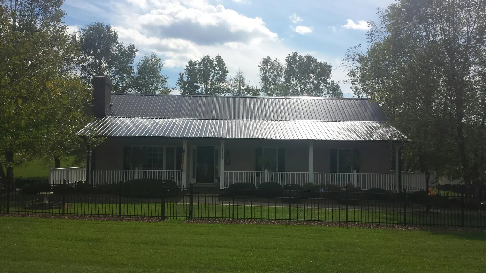 Gray metal roof on a brick ranch with a full width front porch — Gutter Guard Installation work by our crew in Parkton